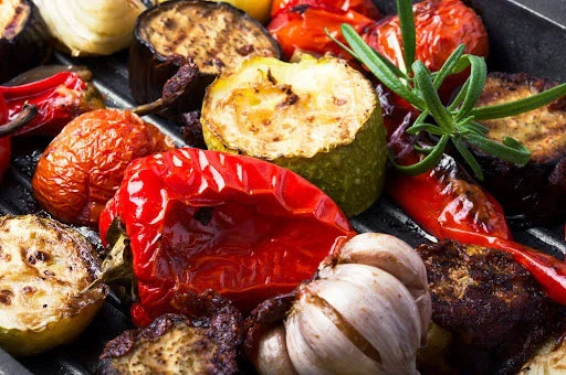 Grilled vegetables including tomatoes, peppers, zucchini, and garlic, perfect for making vegetable soup. Ideal for cooking vegetable soup ingredients