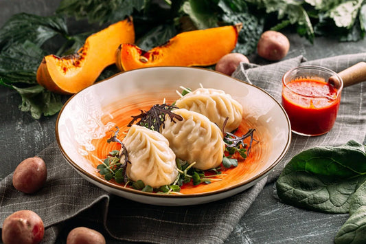 Traditional Turkish mantis served on a plate with fresh greens and a side of dipping sauce - a tasty Turkish manti recipe.
