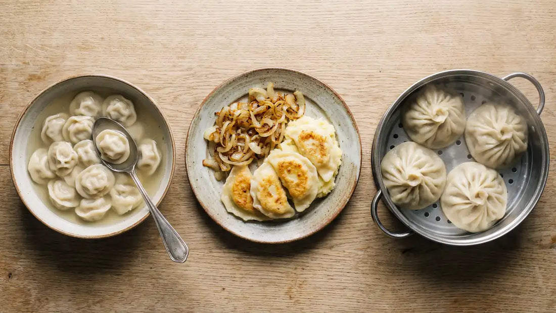 Vergleich dreier traditioneller Gerichte: Pelmeni, Wareniki und Manti auf einem Holztisch.